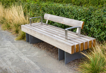 Macro photo of a modern wooden bench in the city park. City improvement, urban planning, public spaces. Wooden garden bench in the city on the background of nature