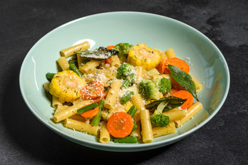 Delicious fresh warm paste sprinkled with cheese parmesan with broccoli, corn, carrots and other vegetables. Vegetarian food