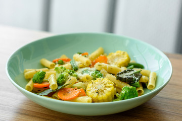 Delicious fresh warm paste sprinkled with cheese parmesan with broccoli, corn, carrots and other vegetables. Vegetarian food