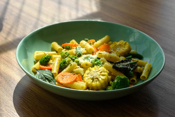 Delicious fresh warm paste sprinkled with cheese parmesan with broccoli, corn, carrots and other vegetables. Vegetarian food