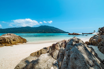 Deserted white sandy tropical beach with rocks
