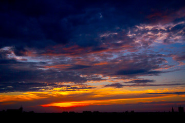 Fototapeta premium Blue sky with white clouds at sunset, town in the distance