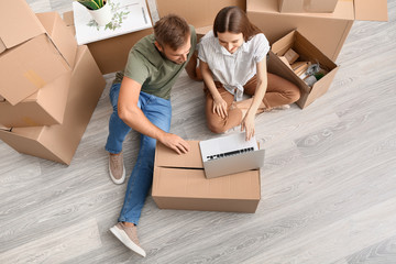 Young couple with laptop planning design of their new house