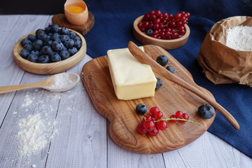 ingredients for baking lie on a light wooden background with a blue kitchen towel. flour, eggs,...