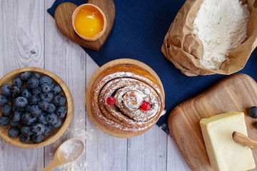 ingredients for baking lie on a light wooden background with a blue kitchen towel. flour, eggs,...
