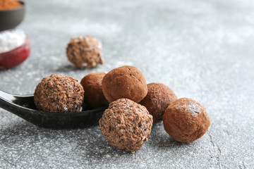 Spoon with tasty sweet truffles on grey background