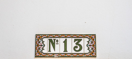 Decorative ceramic house number N13 tile on the wall, characteristic decorative element
