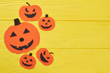 Halloween pumpkin paper silhouettes and copy space. Orange pumpkin paper cut out on yellow background. Holidays, decorations and party concept.