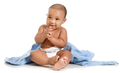 Cute African-American baby with soft towel on white background