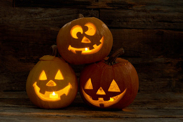 Three funny pumpkins for Halloween. Cute Jack-O-Lantern heads with burning candles inside. Halloween holiday theme.