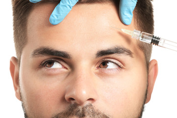 Handsome man receiving filler injection on white background, closeup