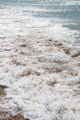 Sea wave, foam and spray. Ocean whitecaps at sandy beach