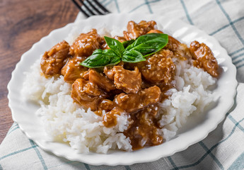 Chicken Breast with sauce and Rice in white plate on a wooden table background