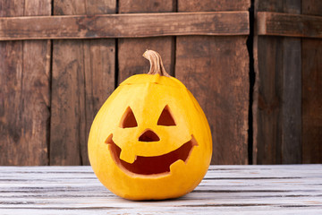 Funny Halloween pumpkin on wooden background. Traditional Halloween pumpkin with smiling face. Halloween symbols and traditions.