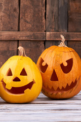 Two Halloween pumpkins on wooden background. Halloween holiday jack lantern. Handmade decoration for seasonal holiday.