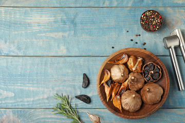 Flat lay composition with black garlic on blue wooden table. Space for text