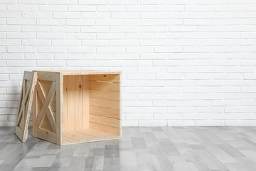 Fototapeta na wymiar Wooden crate on floor at white brick wall. Space for text