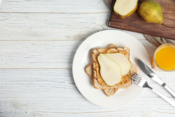 Slice of bread with peanut butter and pear on white wooden table, flat lay. Space for text