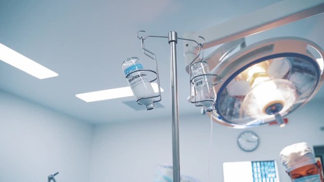 Two chemotherapy bottles hanging from a tripod during operation in clinic. Medical equipment in the operating room.