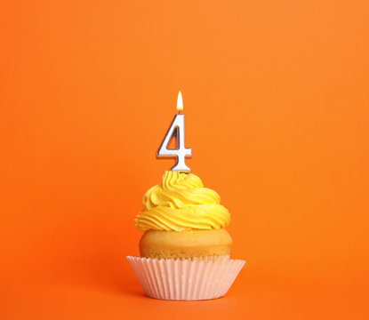 Birthday cupcake with number four candle on orange background