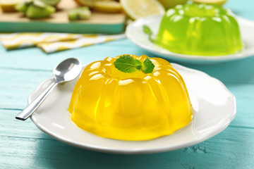 Plate of tasty fruit jelly and mint on blue wooden table, closeup