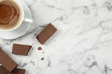 Delicious chocolate wafers with cup of coffee on marble background, top view. Space for text