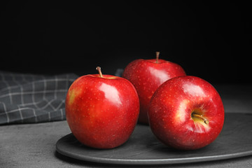 Board with ripe juicy red apples on grey table