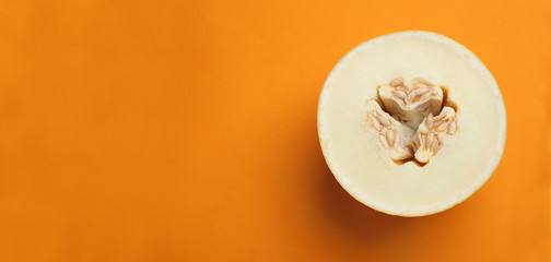 Fototapeta na wymiar Half of ripe tasty melon on orange background, top view. Space for text