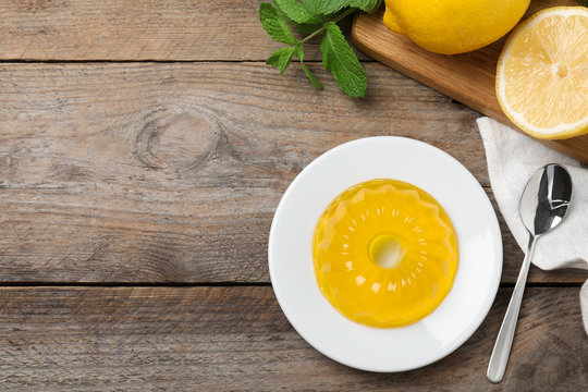 Delicious fresh yellow jelly on wooden table, flat lay. Space for text