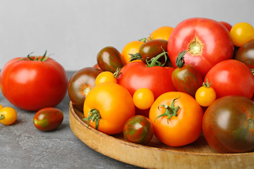 Many fresh ripe tomatoes on grey table