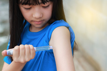 An Asian girl using insulin pen.Self insulin injection.Diabetes in children.