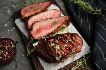 Board with slices of grilled meat on grey table, closeup
