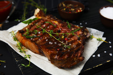 Board with grilled meat on black background, closeup