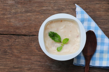 Prune yogurt with pepper mint topping good healthy and delicious in plastic glass on wood table background