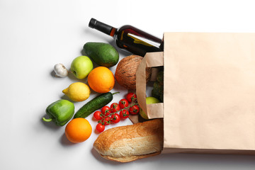 Paper bag with different groceries on white background, top view
