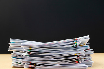 Half of Stack of document paper with colorful paperclip place on wooden table.