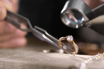 Male jeweler examining diamond ring in workshop, closeup view - obrazy, fototapety, plakaty