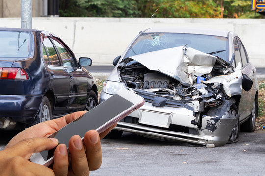 Car insurance agents take pictures of accident-damaged vehicles with a smartphone as a proof of insurance claim.