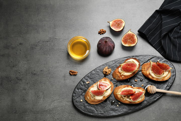Bruschettas with ripe figs and cream cheese served on grey table, flat lay. Space for text
