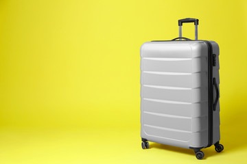 Stylish grey suitcase on yellow background. Space for text