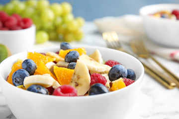 Fresh tasty fruit salad on white marble table, closeup
