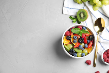 Fresh tasty fruit salad on grey table, flat lay. Space for text