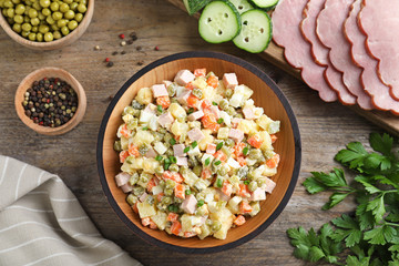 Delicious salad Olivier on wooden table, flat lay