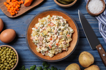 Delicious salad Olivier on blue wooden table, flat lay