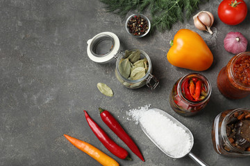 Flat lay composition with products and jars of pickled vegetables on grey table