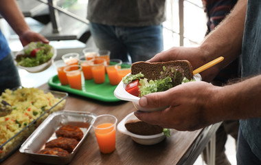 Poor man holding plate with food in charity centre