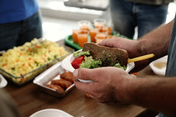 Poor man holding plate with food in charity centre