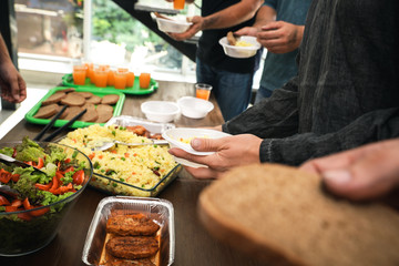 Poor people receiving food from volunteer in charity centre