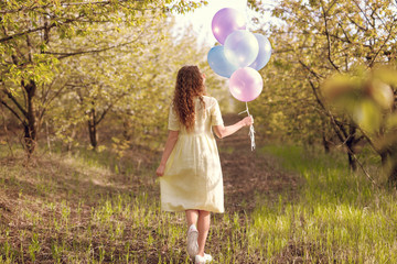 Anonymous woman with balloons in summer garden