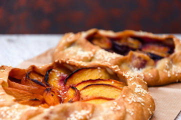 Homemade galettes with peaches and plums with sesame. Sweet fruit pies. Vegetarian dessert. Closeup. Selective focus